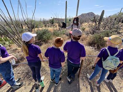 School kids talk to a Raptor Free Flight keeper who is holding a raptor on her glove